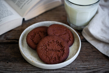  Norwegian Christmas spiced cookies pepperkaker with glass of milk and open book on wooden table .