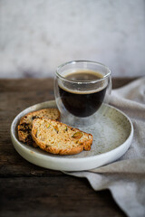 Glass of espresso coffee and homemade biscottis on plate on wooden table.