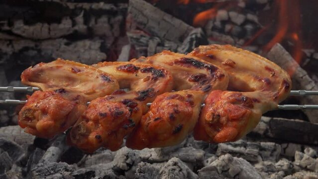 Close-up of the delicious chicken wings on the skewers frying above open fire