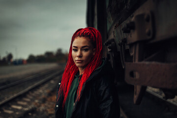 Portrait of a beautiful woman with red hair and dreadlocks at the railway station