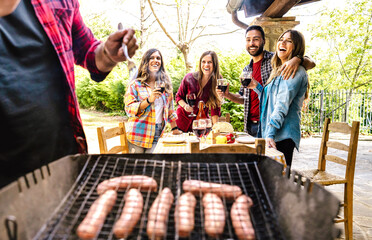 Happy friends having fun grilling meat at barbecue party - Young people eating together at farmhouse restaurant