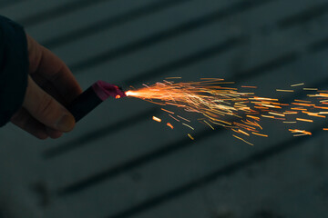 Burning Firecracker with Sparks. Guy Holding a Petard in a Hand. Loud and Dangerous New Year's...