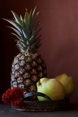 Arrangement with colored fruits, pineapple fruit with green leaves and yellow quinces
