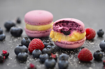 Delicious macaroons and berries on a black tray.