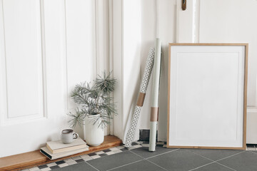 Festive Christmas home decor. Blank vertical wooden picture frame mockup, tiled floor. Pine tree...