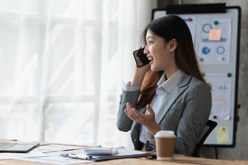 Beautiful asian businesswoman working with cell phone in office. business finance concept