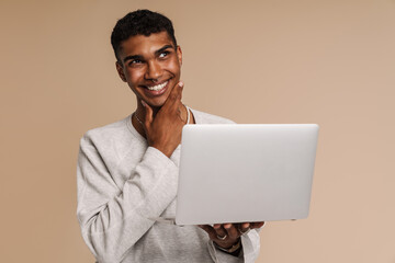 Young black man smiling while working with laptop