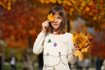 Girl holding a bouquet of autumn leaves in the park
