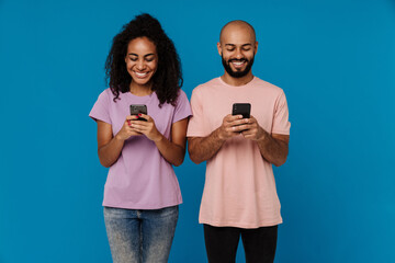 Black man and woman smiling and using cellphones together