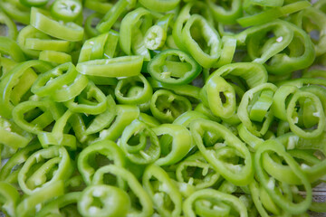 Background of hot green chili pepper cut into pieces.