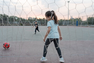 Young girl soccer goalkeeper warding the football goal. Child running for ball in soccer field. Selective focus on boy.