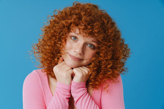 White ginger woman with curly hair smiling and looking at camera
