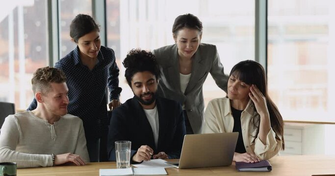 Multi ethnic employees, prepare online presentation, discuss startup ideas, learn new corporate software, using business application staring at laptop screen take part in group meeting in office. Tech