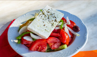 Colouful Greek sallad topped with a big slice of feta cheese from a Greece local restaurant.
