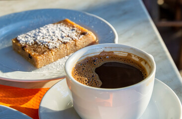 Greek coffee placed on dinning table with Greek cake at background
