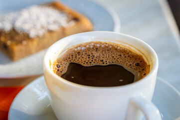 Greek coffee placed on dinning table with Greek cake blurred at background