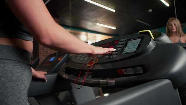 a woman presses start on a treadmill, adjusts the treadmill at the beginning of a workout, pressing a button, a healthy lifestyle