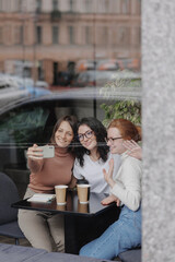 three female friends are talking in a coffee shop and drinking tea, moral support and caring friendship. mental health, group therapy and communication with friends and colleagues. happy or sad women