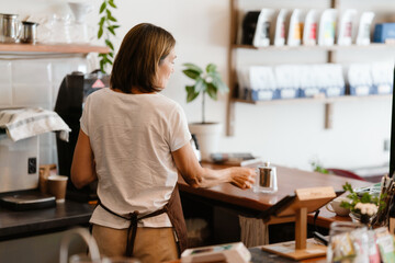 White mature barista woman making tea while working in cafe