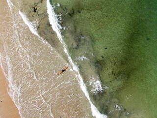 Aerial view of a green water shoreline with a sandy beach
