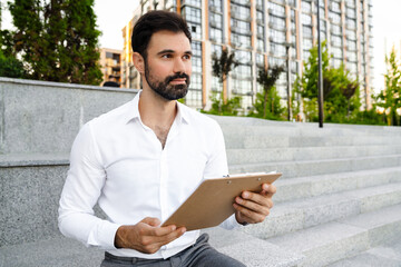 Obraz premium White bearded man working with papers while sitting on bench