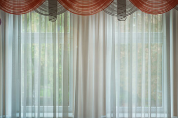 Transparent white curtain with red frill hanging in living room with garden view