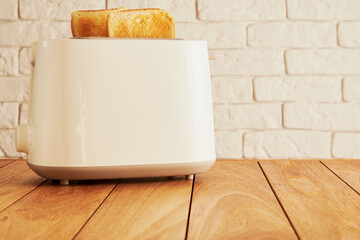 White electric toaster and ready baked bread slices on the wooden kitchen table. Cooking and homeware technologies backgrounds