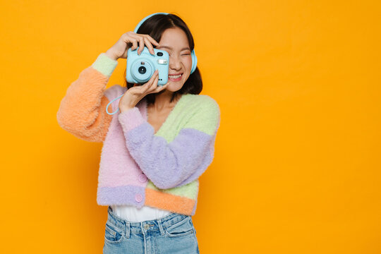 Asian young woman in headphones taking photo on instant camera