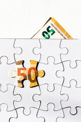 Money is found in the missing pieces of a jigsaw puzzle. 50 euros were found by solving the...