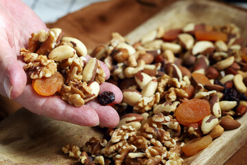 A handful of nuts and dried fruits in male palms. Healthy sweets or snack.