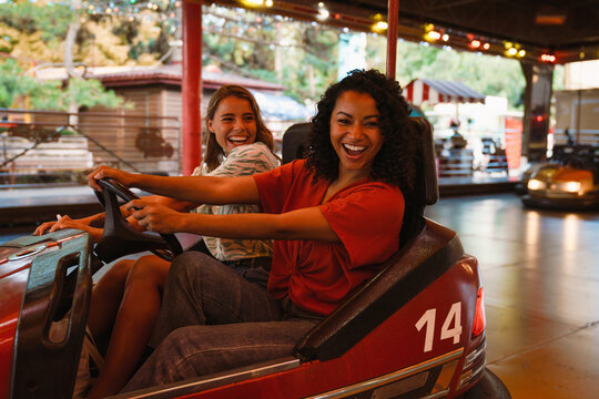 Young beautiful enthusiastic girls riding bump car in amusement park