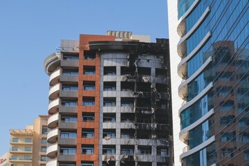 Fire insurance. Charred burnt residential high-rise building wall after fire. Ash and soot on skyscraper wall surface, windows, balconies after blaze.City fire