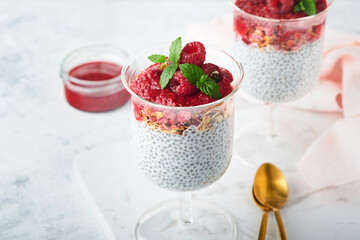 Chia pudding. Healthy vanilla chia pudding in glass with fresh raspberries and mint on white background. Vegan healthy breakfast.