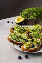 Vegetarian green sandwiches with avocado and cucumber with microgreens on a light background