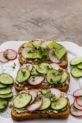 Three sandwiches with vegetables and vegetable cheese on a white square plate