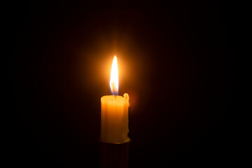 white burning candle on a black background, blackout