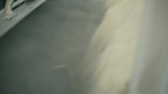 Close-up of pouring flour into industrial mixer. Clip. Filling mixing tank and kneading dough. Filling flour into industrial dough mixer
