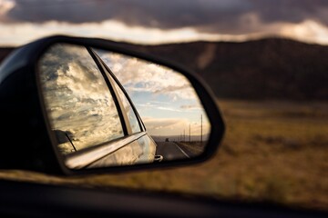 Close-up shot of the car mirror reflecting the cloudy sky