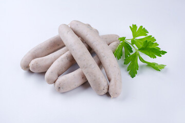 Traditionelle rohe Schweinsbratwurst angeboten als close-up auf einem weißen Board mit...