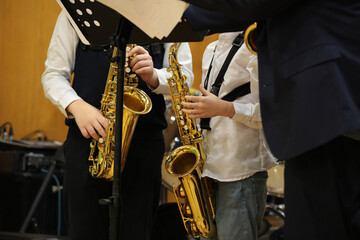 Musicians young students playing the saxophone stand in front of the notes in class in a school classroom with a teacher