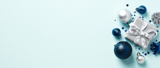 Christmas banner with copy space. Silver gift box, balls, confetti on pastel blue background. Christmas header, greeting card design.