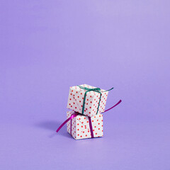 Wrapped Gift box with colorful ribbon on bright purple background with copy space. Creative realistic minimal gift for Christmas or Holiday giving concept. Visual aesthetic concept.