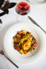 Appetizing Italian pasta with duck meat on a light background. Beautiful serving. Exquisite presentation of food.