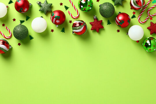 Christmas frame top border with Christmas balls, candy canes, confetti on light green background. Happy New Year greeting card template.