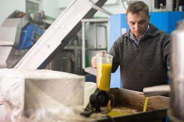 Confident male worker controlling quality of olive oil of traditional cold pressing on artisanal...