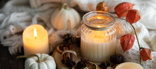 Obraz na płótnie Canvas Autumn home composition with aromatic candle, dry citrus, cinnamon, anise. Aromatherapy on a grey fall morning, atmosphere of cosiness and relax. Wooden background close up banner