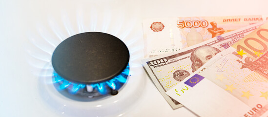 Russian banknotes against the background of euro bills and a gas burner. Gas crisis concept.