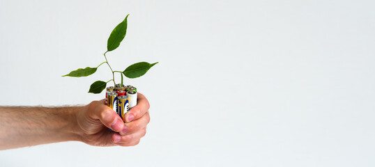 Leaf grows from a Alkaline batteries in hand. Green energy a symbol of clean energy resources....