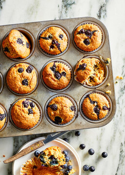 Blueberry muffins on marble with plate.