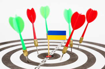 Darts with the flag of Ukraine in the bullseye, next to red and green darts.